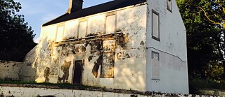 A building with scarred facade sits in bright sunlight