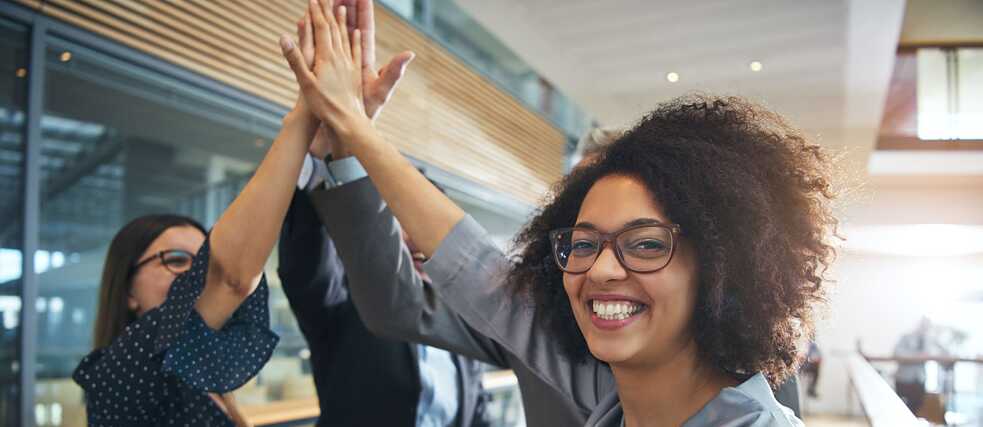 Vier Kollegen die sich zusammen freuen und sich ein High-Five geben