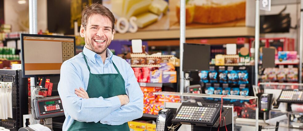 A cashier stands behind his counter and smiles