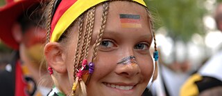 Nahaufnahme eines Mädchens mit Strirnband in den deutschen Nationalfarben.