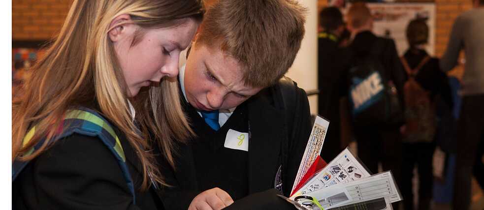2 students eagerly looking at a tablet 