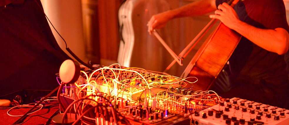 Musician playing a cello in front of a sound system