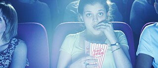 Eine Zuschauerin isst Popcorn bei einer spannenden Filmvorführung.