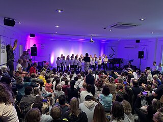 The children's choir of the German International School Sydney perform on stage and a big audience is watching