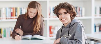 Ein junger Mann sitzt am Tisch in einer Bibliothek