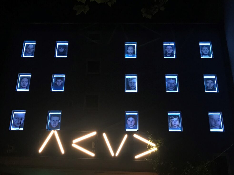 15 Fenster zeigen jeweils das Portrait eines Kindes aus der Serie "Das Land der Kinder" von Helen Bozhko. Die beleuchteten Fotos waren in der Nacht von weitem gut erkennbar.