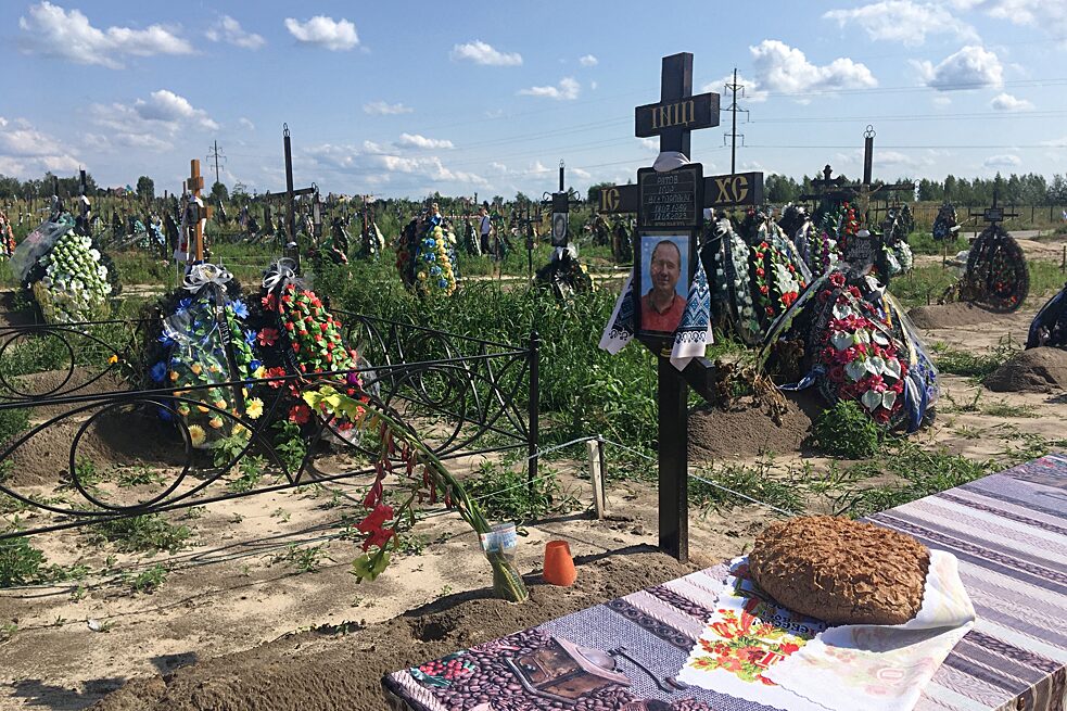 Friedhof in Butscha, Oblast Kyjiw, Juli 2023: Angehörige haben einem Toten auf dem Feld für die Opfer der russischen Besatzung 2022 einen Kuchen mitgebracht.