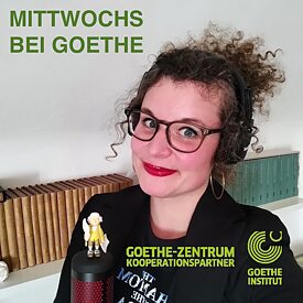 Autorin des Podcasts mit schwarzen Kopfhörern; vor ihr steht ein Mikrofon, auf dem eine kleine Goethefigur sitzt
