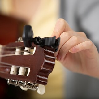 Ein Mann stimmt eine Gitarre.