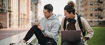 Zwei junge Männer mit Laptop und Notizblock