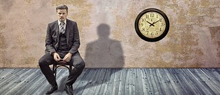 Man in a suit sitting next to a clock