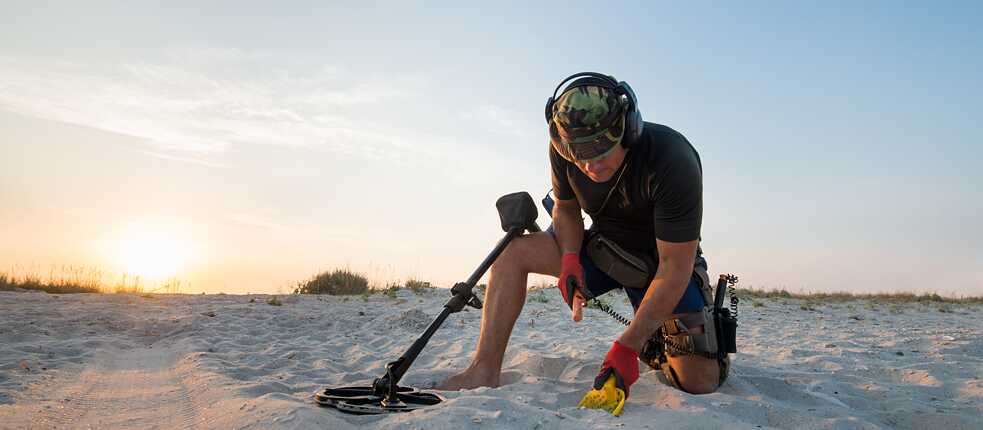 Prospector on the beach searching with a shovel