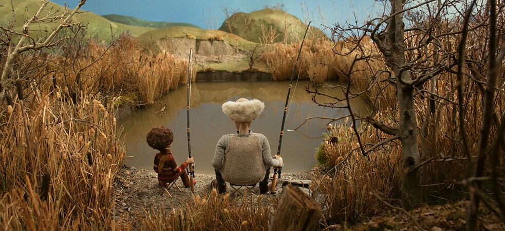 Ein Junge und ein alter Mann sitzen am See und angeln.