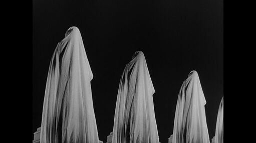Four figures in white cloths standing at intervals against a black background