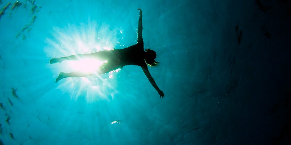 Eine junge Frau lässt sich im Meer treiben.