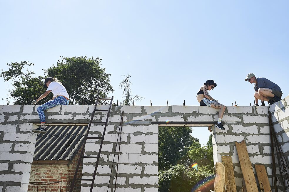 Tím dobrovoľníčok pracuje na novopostavených múroch domu pani Niny v Lukašivke.