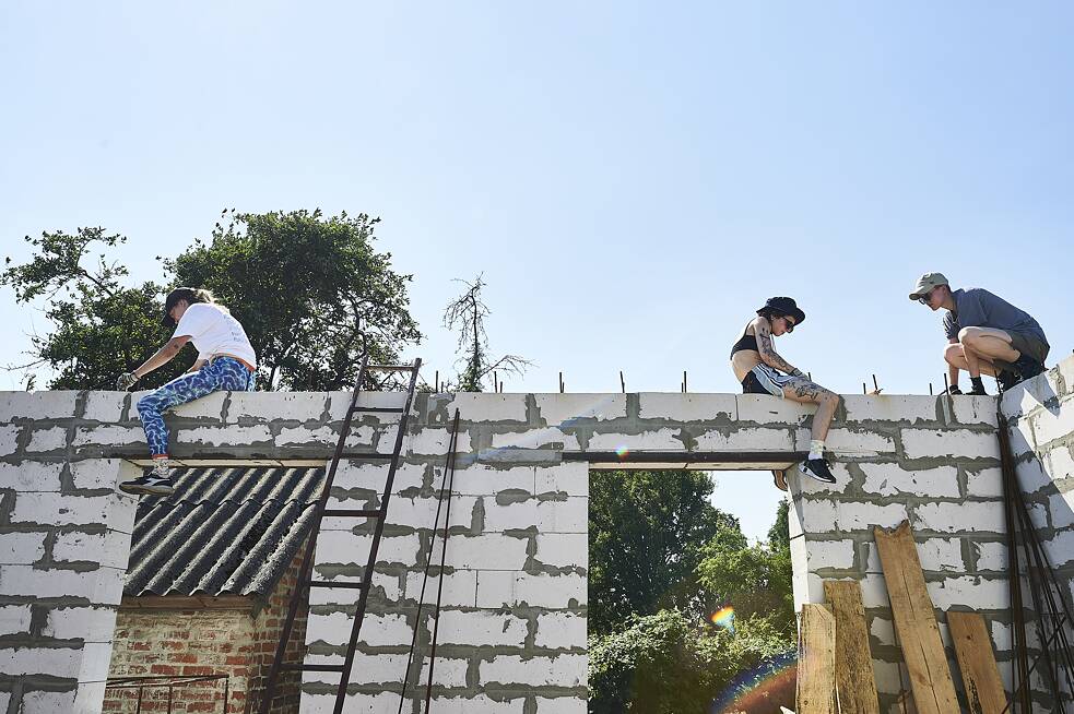 Ein Team von Freiwilligen arbeitet an den neu errichteten Wänden von Ninas Haus in Lukaschiwka.