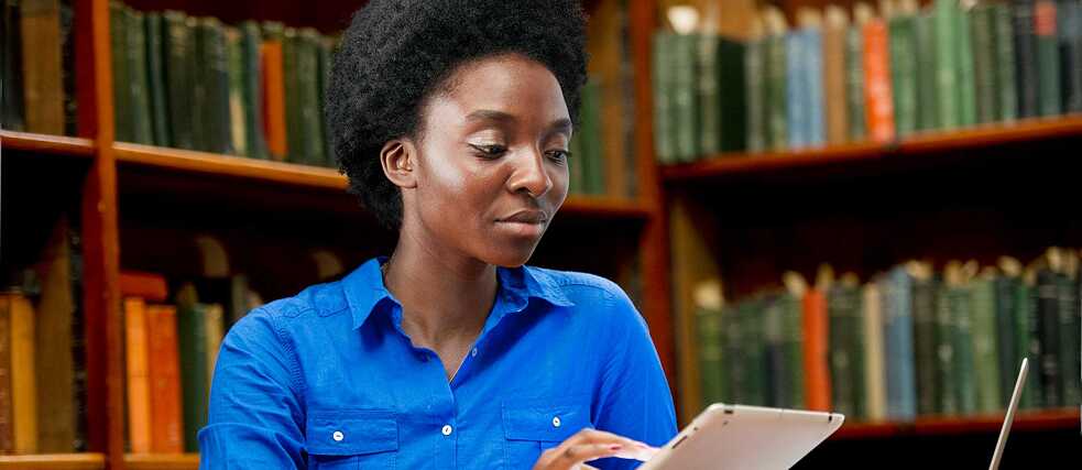 A course participant studies in the library using the online platform on her tablet.