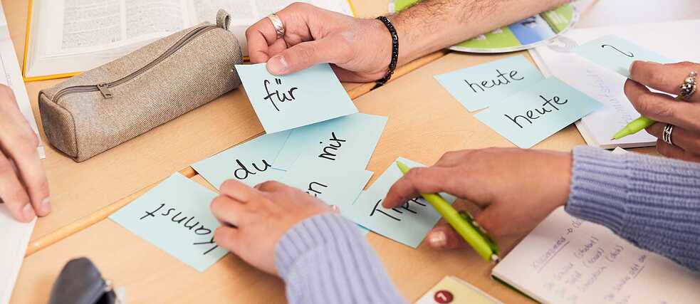 Laid out on a table are word cards which learners can use to build sentences. 