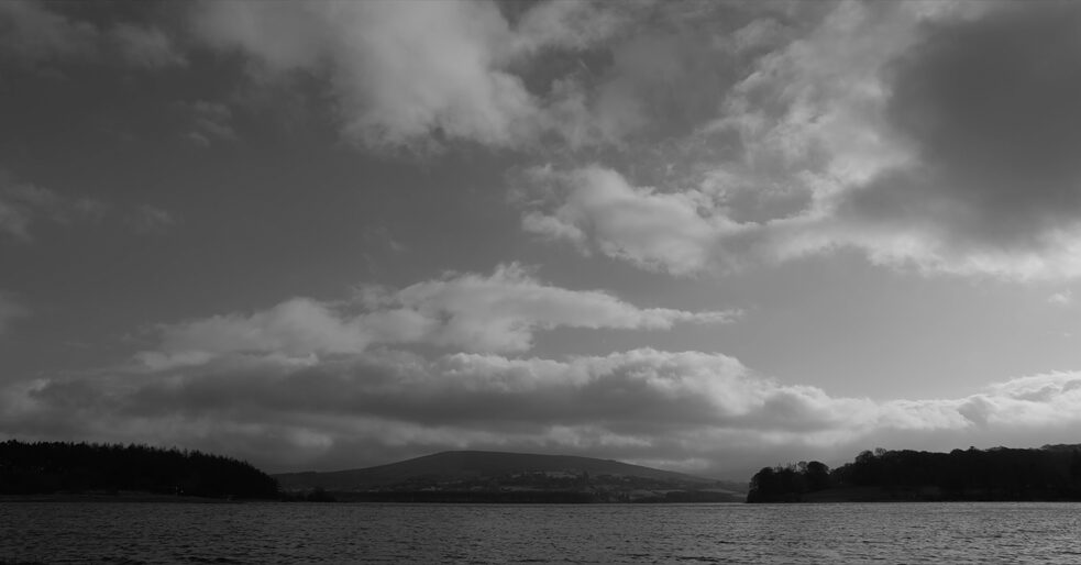 Schwarz-weiß Bild eines Sees mit Bergen im Hintergrund