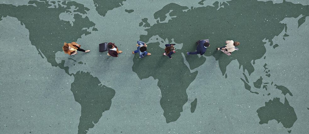 Geschäftsleute laufen mit Rollkoffern über Weltkarte