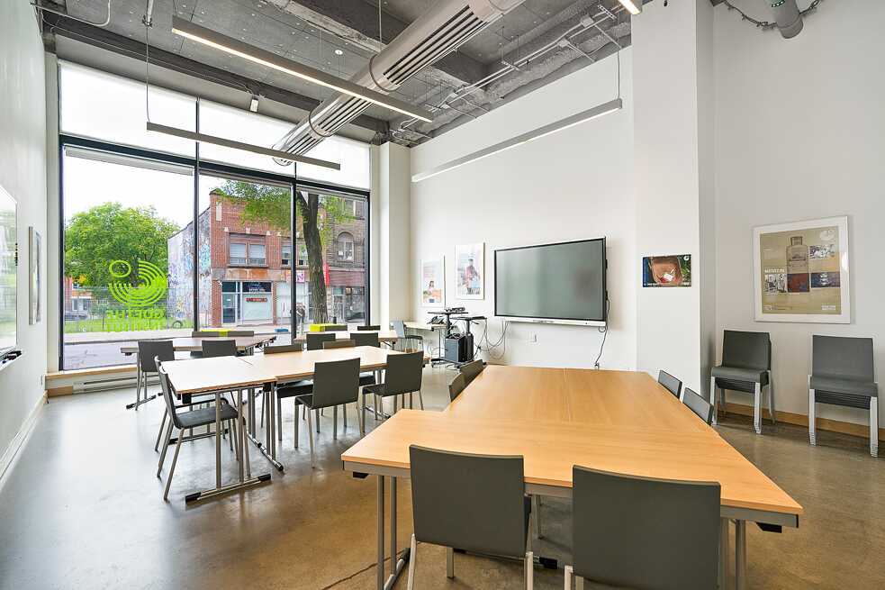 An expansive room with multiple tables and chairs set before a large window, creating a bright and inviting atmosphere.