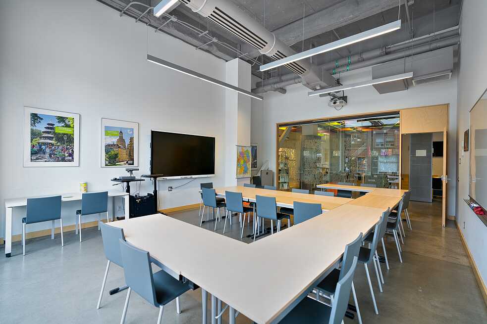 A large meeting room equipped with several big tables and multiple chairs, ideal for group meetings and presentations.