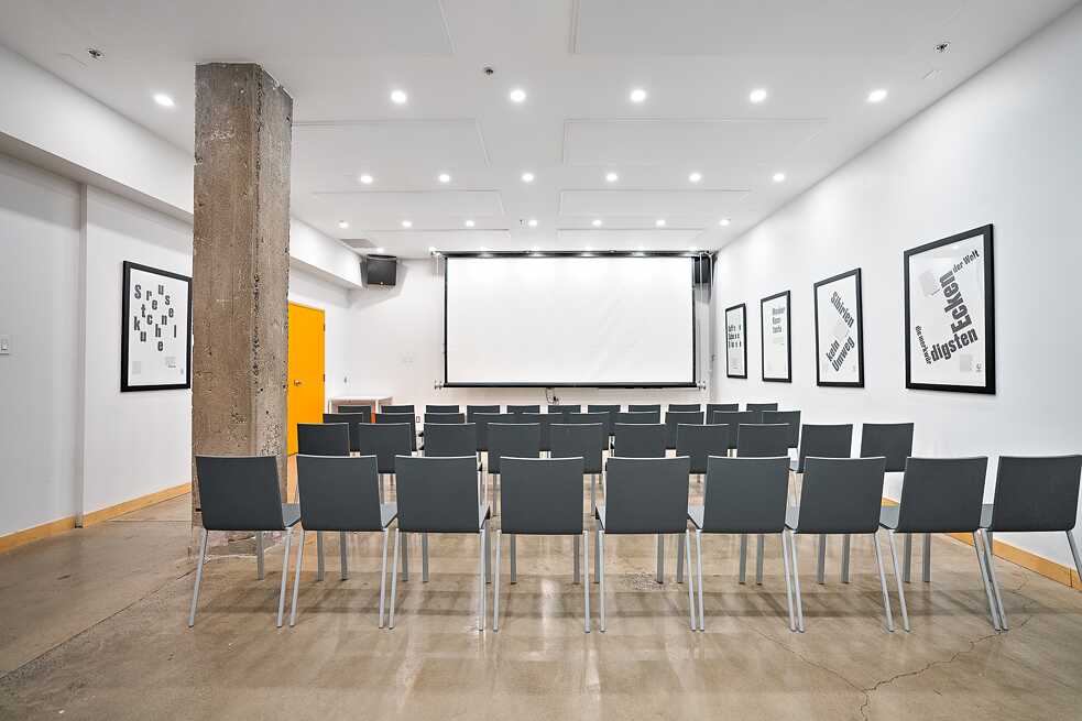 Multifunctional  conference room showcasing chairs and a large projector screen, set up for an engaging meeting or seminar.