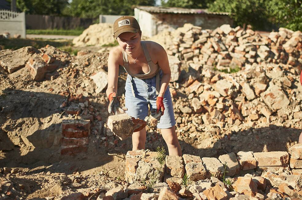 Die Projektleiterin Jana wirft Steine in die Mitte des zukünftigen Fundaments.