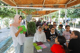 Eine junge Frau gibt Deutschunterricht vor Jugendlichen im Freien