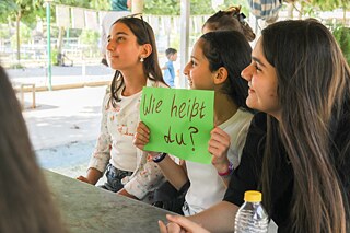 Zwei Jugendliche halten ein Schild mit einer Frage auf Deutsch