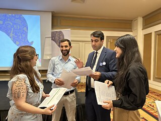 Vier junge Menschen tauschen sich zum Sprachkurs aus und lachen