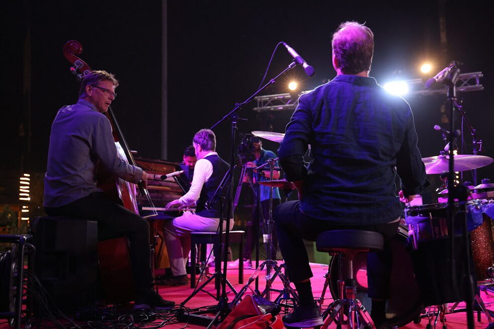 Blick von hinten auf drei männliche Musiker auf der Bühne