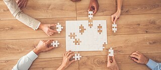 Hände mit den Puzzlesteilen