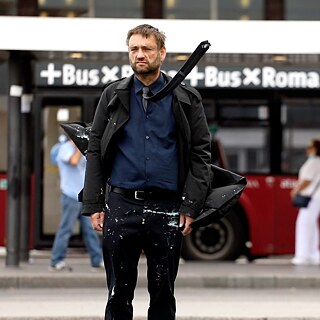 Filmstill aus „Inizio” von Erik Schmidt, ein Mann spaziert die Straße entlang