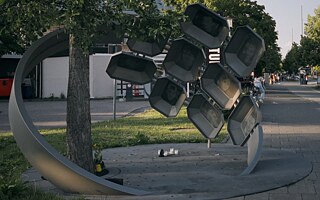 Ein Denkmal am Olympia Einkaufszentrum München erinnert an den rassistischen Anschlag. Der Edelstahlring mit den Porträts und Namen der neun Todesopfer umschließt einen Gingko Baum.