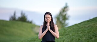 Eine junge Frau meditiert in der Natur