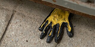 Ein Handschuh schaut unter einem rostigen Container hervor