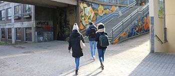 Zeigt zwei Jugendliche in der Stadt vor einer Graffitiwand.