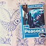 Das Buch 'The Peacock' liegt auf einem besticktem weißen Kissen