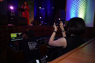 junge Frau fotografiert die Performance auf der Bühne