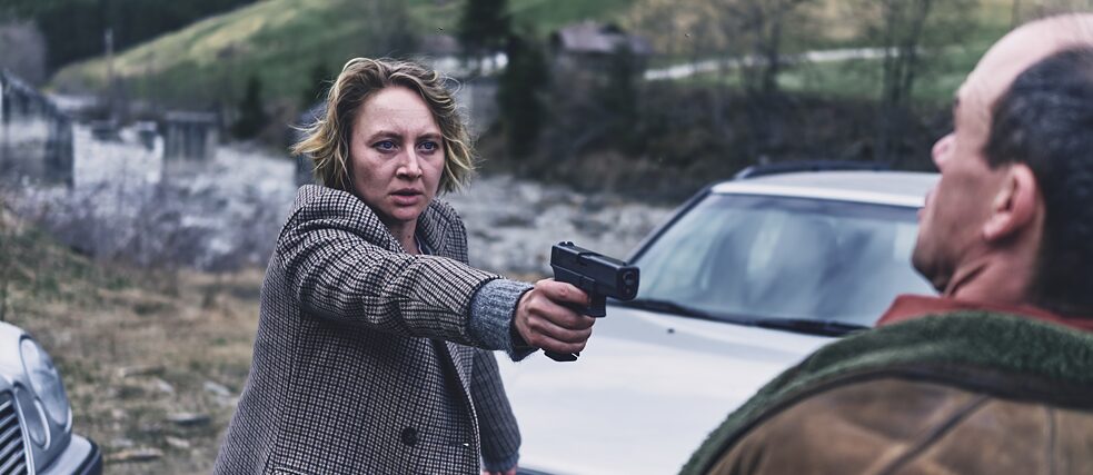 Blum (Anna Maria Mühe) bedroht Sebastian Hackspiel (Gerhard Liebmann) mit einer Waffe und will sein "vermeintliches" Brandmal sehen.