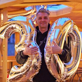 Alumnus Oleg Dmitrijev, holding balloons which result in the number 30 for the anniversary of the Europanetzwerk Deutsch