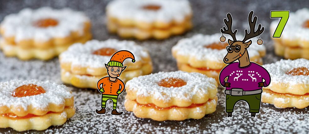 Rentier Matilda und Wichtel Karl stehen zwischen frisch gebackenen Plätzchen