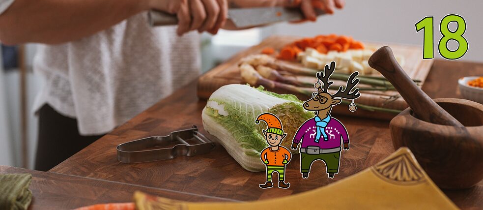 Rentier Matilda und Wichtel Karl stehen in der Küche auf einer Arbeitsplatte und beobachten eine Person beim Schneiden von Gemüse