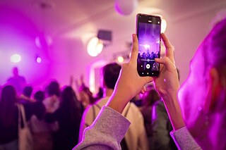 Studentka si fotí koncert mobilním telefonem.