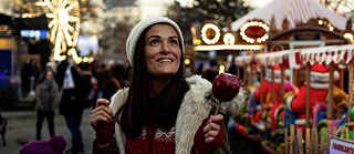 Габріела в Німеччині. Ввечері вона йде прогулятись на різдвяний ярмарок. В руці вона тримає червоне карамелізоване яблуко