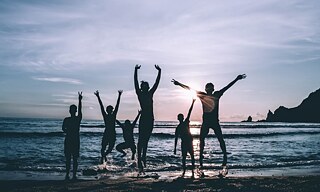 Mehrere Menschen am Meer springen in die Luft.