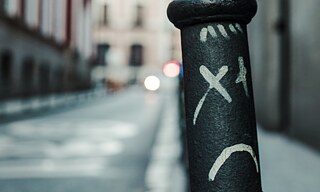 Ein Straßenpfosten mit einem aufgemalten trautigen Gesicht