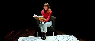 In der Bibliothek hören Kinder einer Frau beim Geschichtenerzählen zu